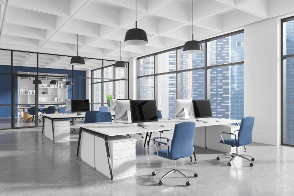 A white office with white deskps, computers, and blue computer chairs