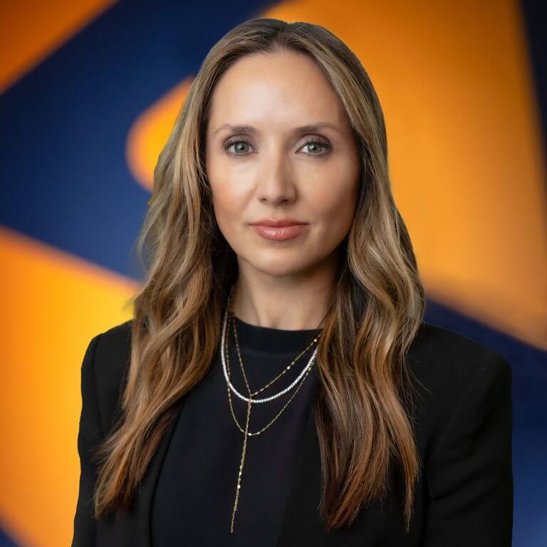 A woman with long wavy hair with necklaces in a black shirt