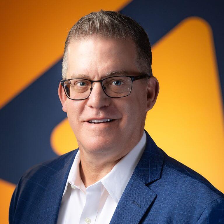A many in blue striped suit, white shirt, with glasses in front of blue and orange background.